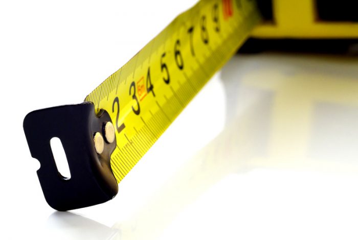 Self-retracting tape measure on white background, closeup, shallow depth of field